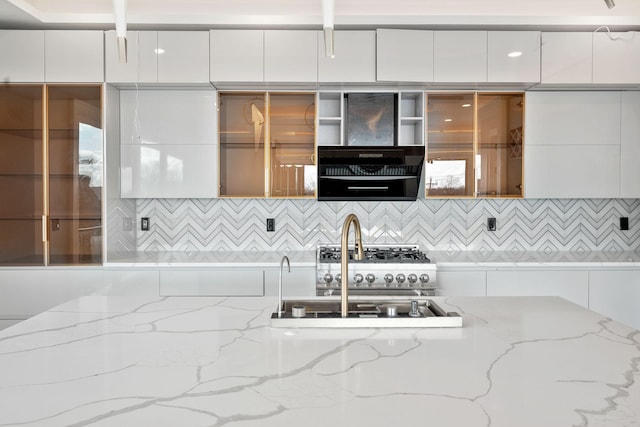 kitchen with white cabinetry, wall chimney exhaust hood, light stone countertops, and sink