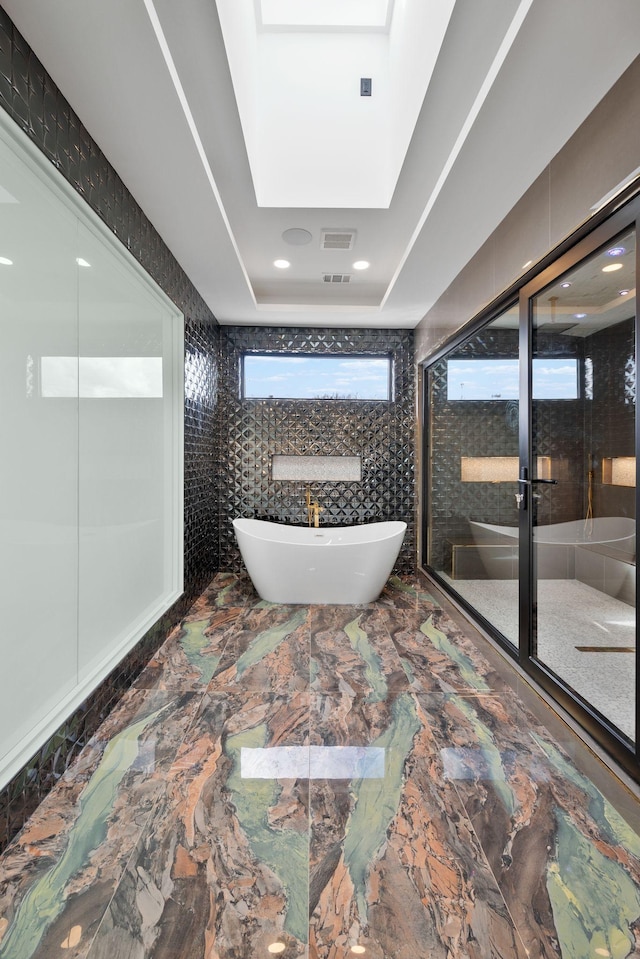 bathroom featuring a tray ceiling and shower with separate bathtub