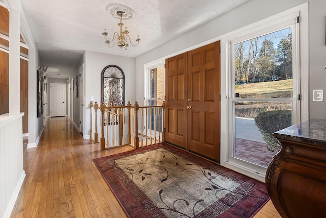 foyer entrance featuring an inviting chandelier, light hardwood / wood-style floors, and a textured ceiling