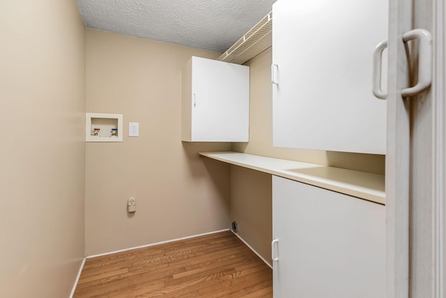 clothes washing area with washer hookup, light hardwood / wood-style floors, and a textured ceiling