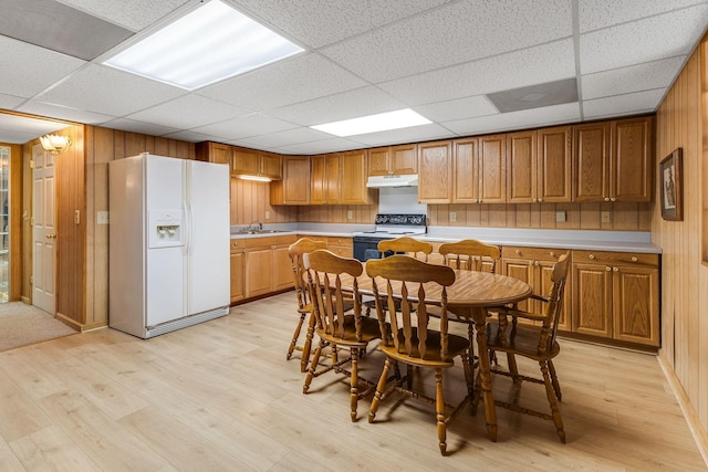 kitchen featuring white appliances, wooden walls, a paneled ceiling, and light hardwood / wood-style flooring