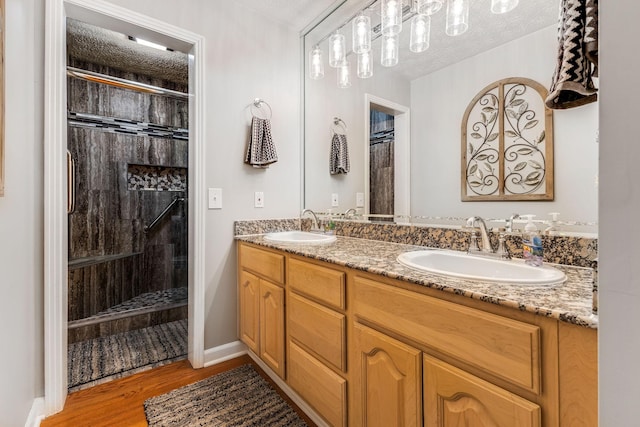 bathroom with hardwood / wood-style flooring, tiled shower, vanity, and a textured ceiling