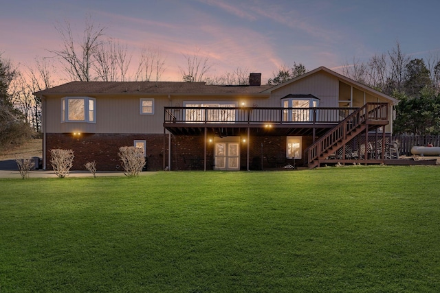 back house at dusk featuring a yard and a deck