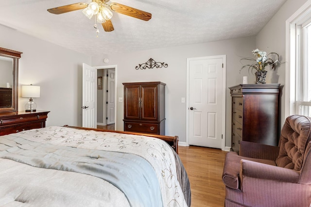 bedroom with a textured ceiling, multiple windows, and light wood-type flooring