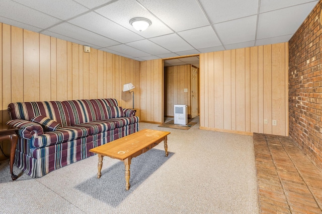 living room featuring wood walls, brick wall, heating unit, and a drop ceiling