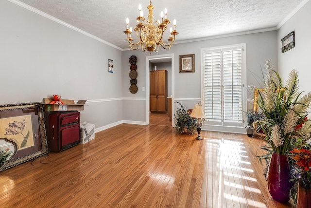 misc room with crown molding, wood-type flooring, a textured ceiling, and a notable chandelier