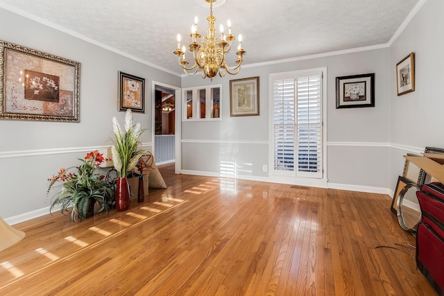 living area featuring crown molding, an inviting chandelier, hardwood / wood-style floors, and a textured ceiling