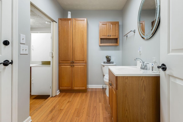 bathroom with vanity, toilet, hardwood / wood-style floors, and a textured ceiling