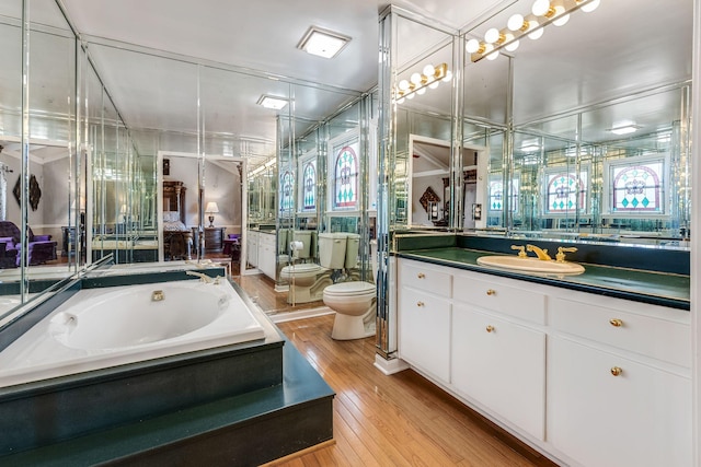 bathroom featuring a bidet, hardwood / wood-style flooring, vanity, toilet, and a bathing tub