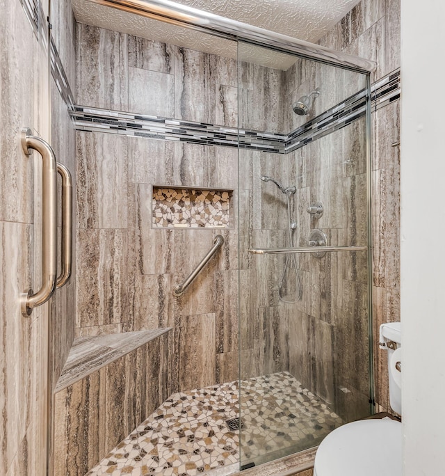 bathroom featuring walk in shower, toilet, and a textured ceiling