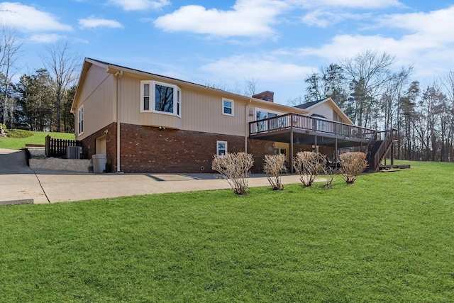 back of property with a wooden deck, a garage, and a lawn