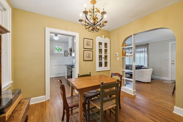 dining area with hardwood / wood-style flooring, a healthy amount of sunlight, and an inviting chandelier