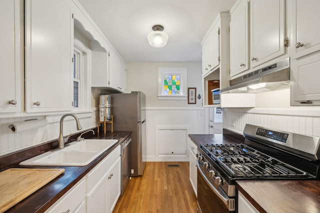 kitchen with stainless steel appliances, sink, white cabinets, and butcher block countertops