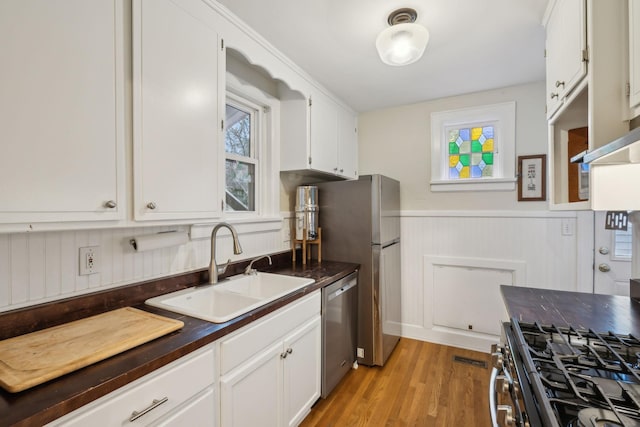 kitchen featuring light wood-type flooring, stainless steel appliances, sink, and white cabinets