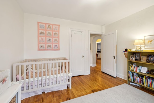 bedroom featuring a nursery area and light hardwood / wood-style flooring