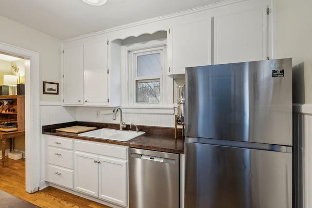 kitchen featuring stainless steel appliances, light hardwood / wood-style floors, sink, and white cabinets