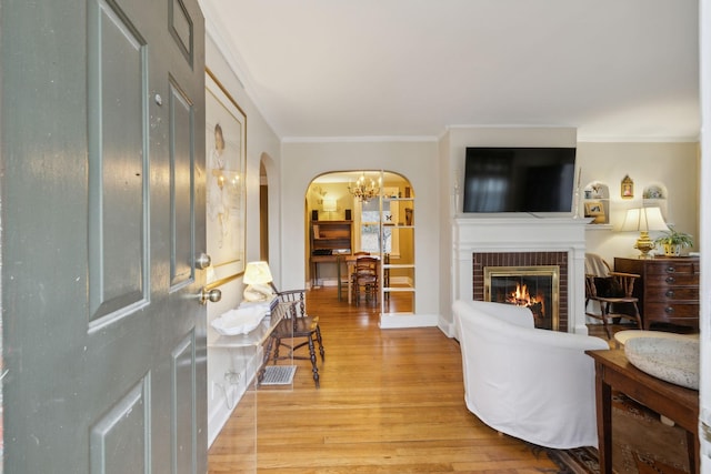 living room with hardwood / wood-style flooring, ornamental molding, and a fireplace