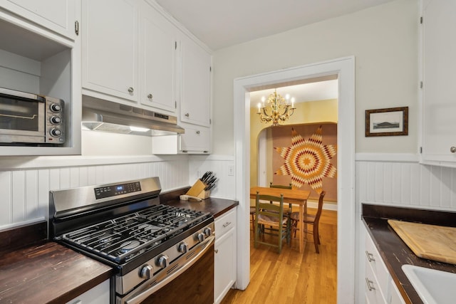 kitchen featuring stainless steel gas range, sink, an inviting chandelier, light hardwood / wood-style flooring, and white cabinets