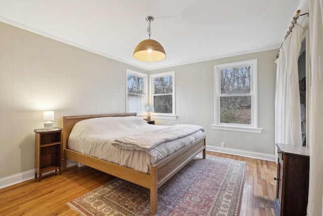 bedroom featuring hardwood / wood-style flooring, ornamental molding, and multiple windows