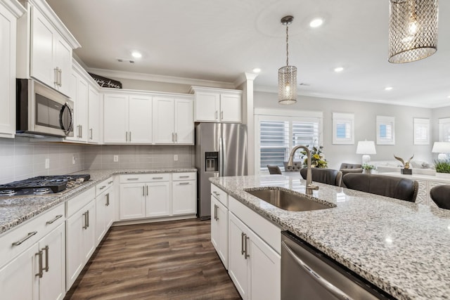 kitchen with sink, hanging light fixtures, white cabinets, and appliances with stainless steel finishes