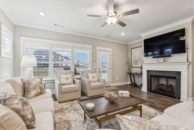 living room featuring ceiling fan, crown molding, wood-type flooring, and a healthy amount of sunlight