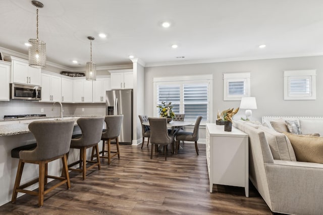 kitchen with pendant lighting, appliances with stainless steel finishes, light stone counters, and white cabinets