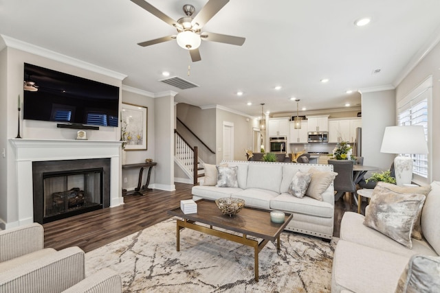 living room with crown molding, dark hardwood / wood-style floors, and ceiling fan