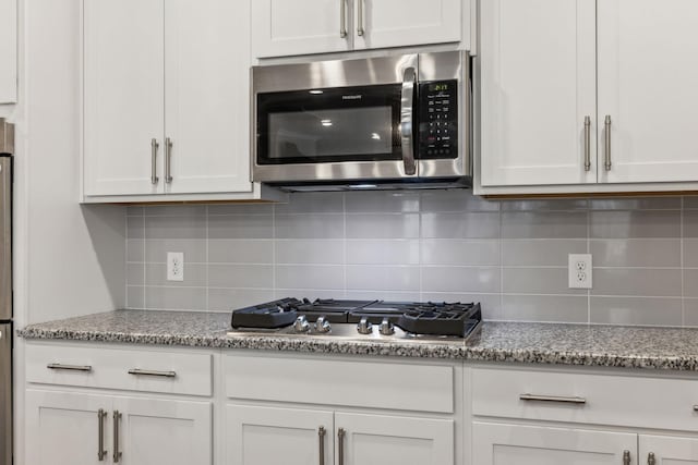 kitchen featuring white cabinetry, light stone counters, and appliances with stainless steel finishes