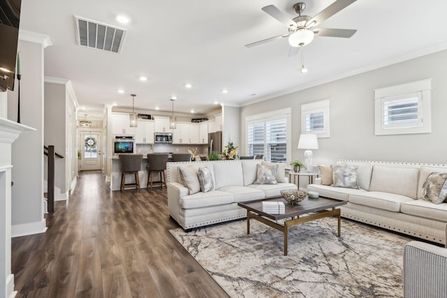 living room with ceiling fan, crown molding, a wealth of natural light, and dark wood-type flooring