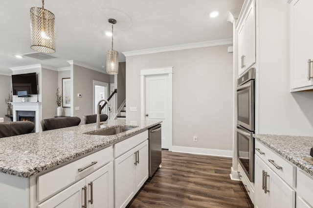 kitchen with white cabinetry, sink, hanging light fixtures, stainless steel appliances, and a center island with sink