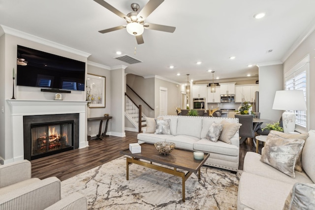 living room featuring dark wood-type flooring, ceiling fan, and ornamental molding