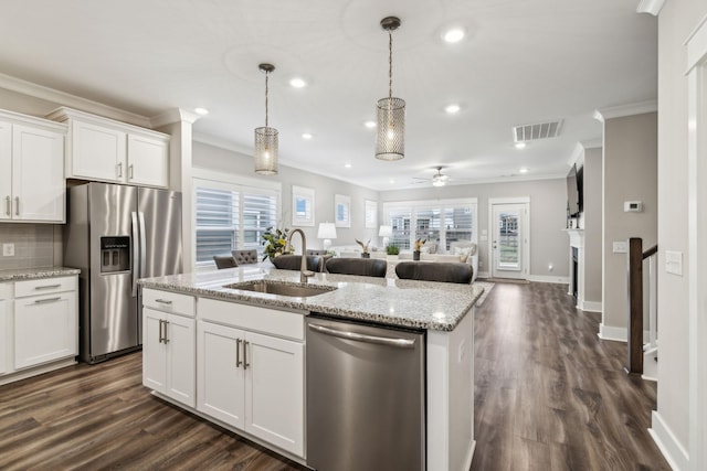 kitchen featuring sink, appliances with stainless steel finishes, pendant lighting, a kitchen island with sink, and white cabinets