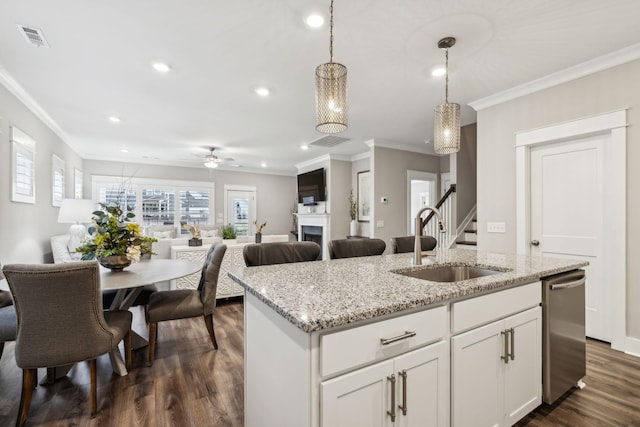 kitchen featuring decorative light fixtures, dishwasher, white cabinetry, sink, and a center island with sink