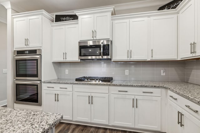 kitchen featuring white cabinetry, appliances with stainless steel finishes, light stone counters, and decorative backsplash