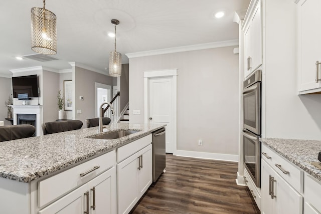 kitchen with white cabinetry, sink, hanging light fixtures, stainless steel appliances, and a center island with sink