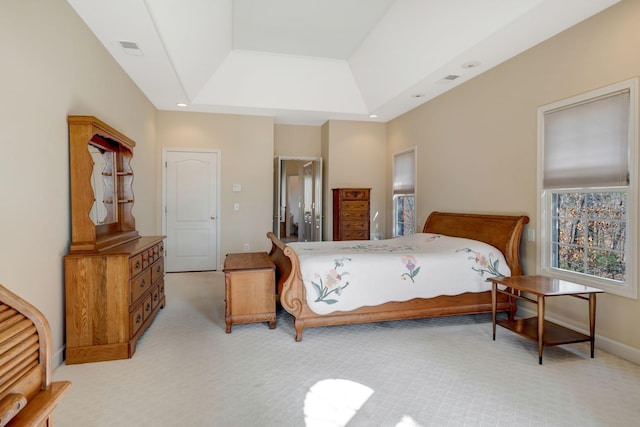 bedroom with a raised ceiling and light carpet