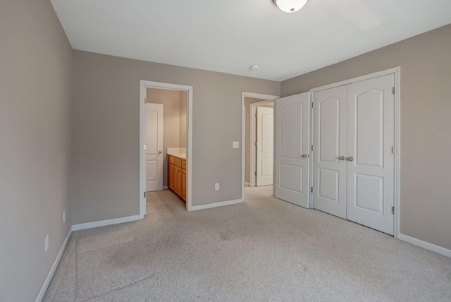 unfurnished bedroom featuring ensuite bathroom, light carpet, and a closet