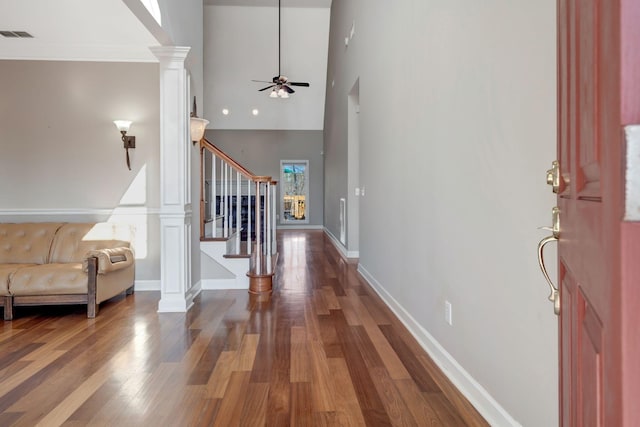 entryway with ceiling fan, a towering ceiling, hardwood / wood-style floors, and ornate columns