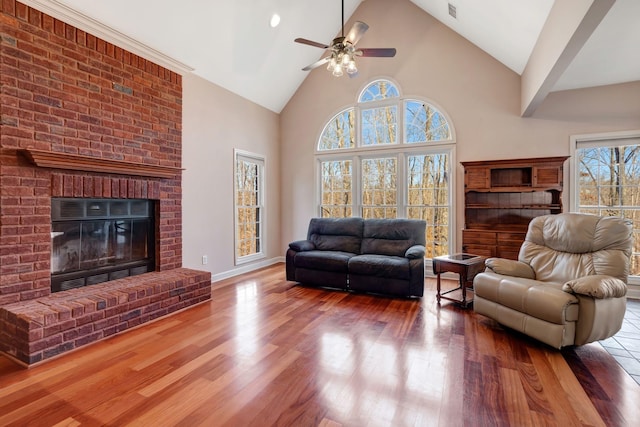 living room featuring hardwood / wood-style flooring, a fireplace, high vaulted ceiling, and ceiling fan