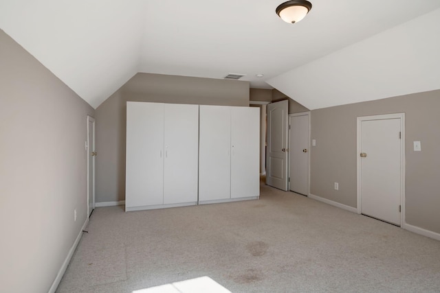 additional living space featuring light colored carpet and vaulted ceiling