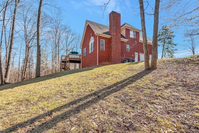 view of side of property with a wooden deck, a garage, and a lawn