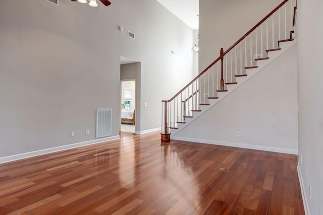 unfurnished living room featuring ceiling fan, hardwood / wood-style floors, and a high ceiling