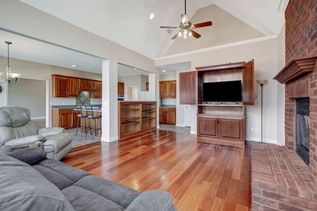 living room with hardwood / wood-style flooring, high vaulted ceiling, a fireplace, and ceiling fan with notable chandelier