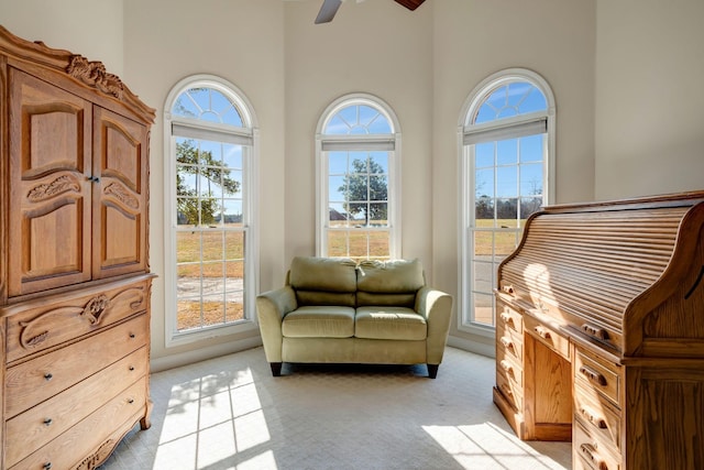 sitting room with ceiling fan, light colored carpet, and a healthy amount of sunlight