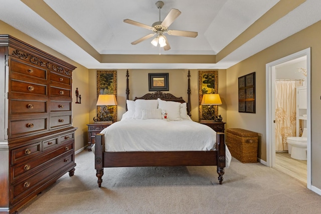 carpeted bedroom featuring ceiling fan, connected bathroom, and a tray ceiling