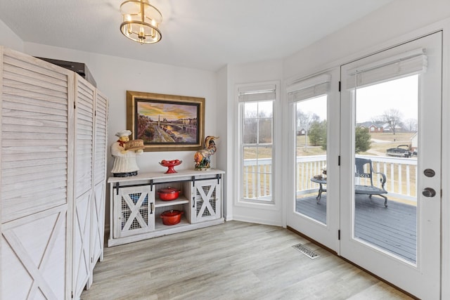 doorway to outside with light hardwood / wood-style flooring and a chandelier