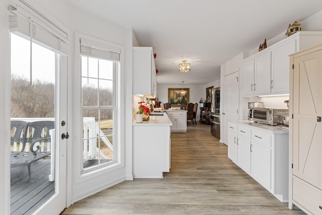 kitchen featuring kitchen peninsula, sink, light hardwood / wood-style flooring, and white cabinets