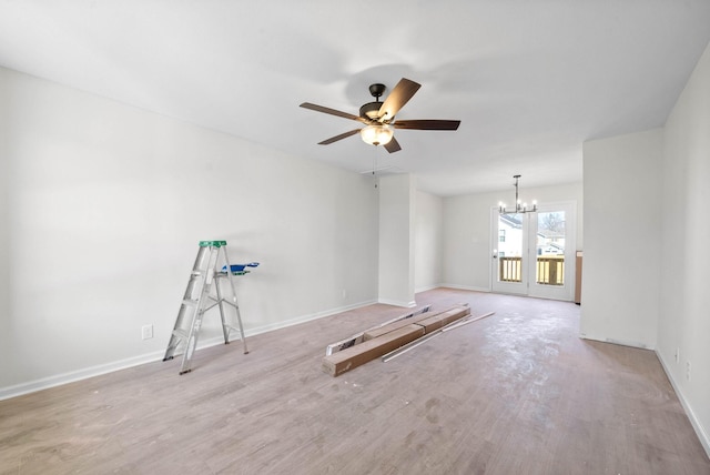 empty room with ceiling fan with notable chandelier and light wood-type flooring