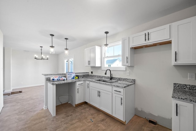 kitchen featuring pendant lighting, sink, hardwood / wood-style floors, white cabinets, and kitchen peninsula