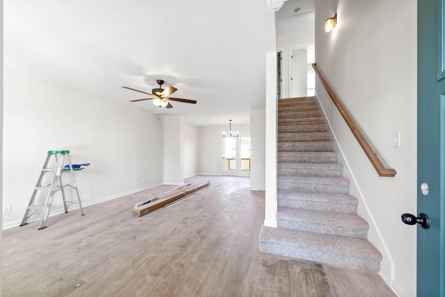 stairs with wood-type flooring and ceiling fan with notable chandelier